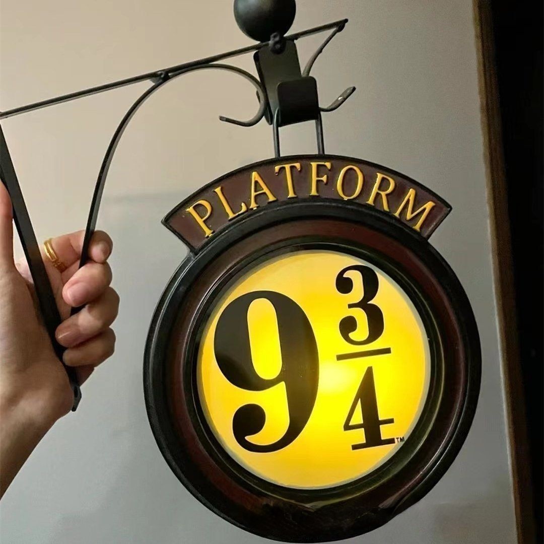 Harry Potter Night light with bracket for mounting to the wall being held by a hand. Night Light has a yellow lens that the light shines through